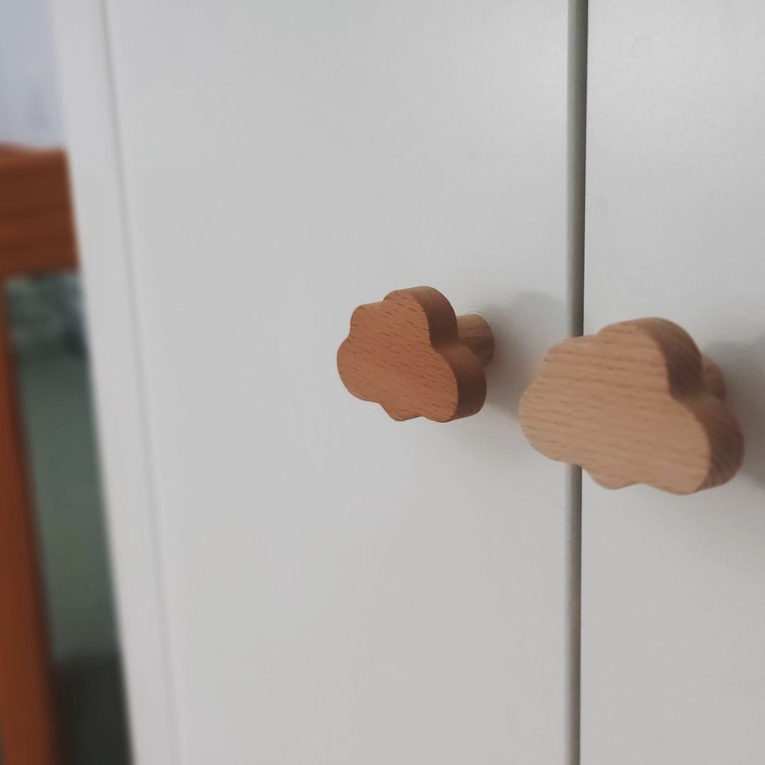 Tiradores infantiles en forma de nube instalados en un armario de bebé, símbolo de esperanza y nueva vida